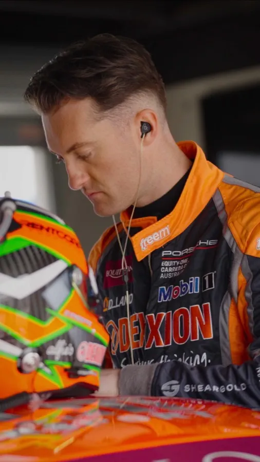 Dylan O’Keeffe in his Dexion race suit, earphones in, looking down beside his helmet
